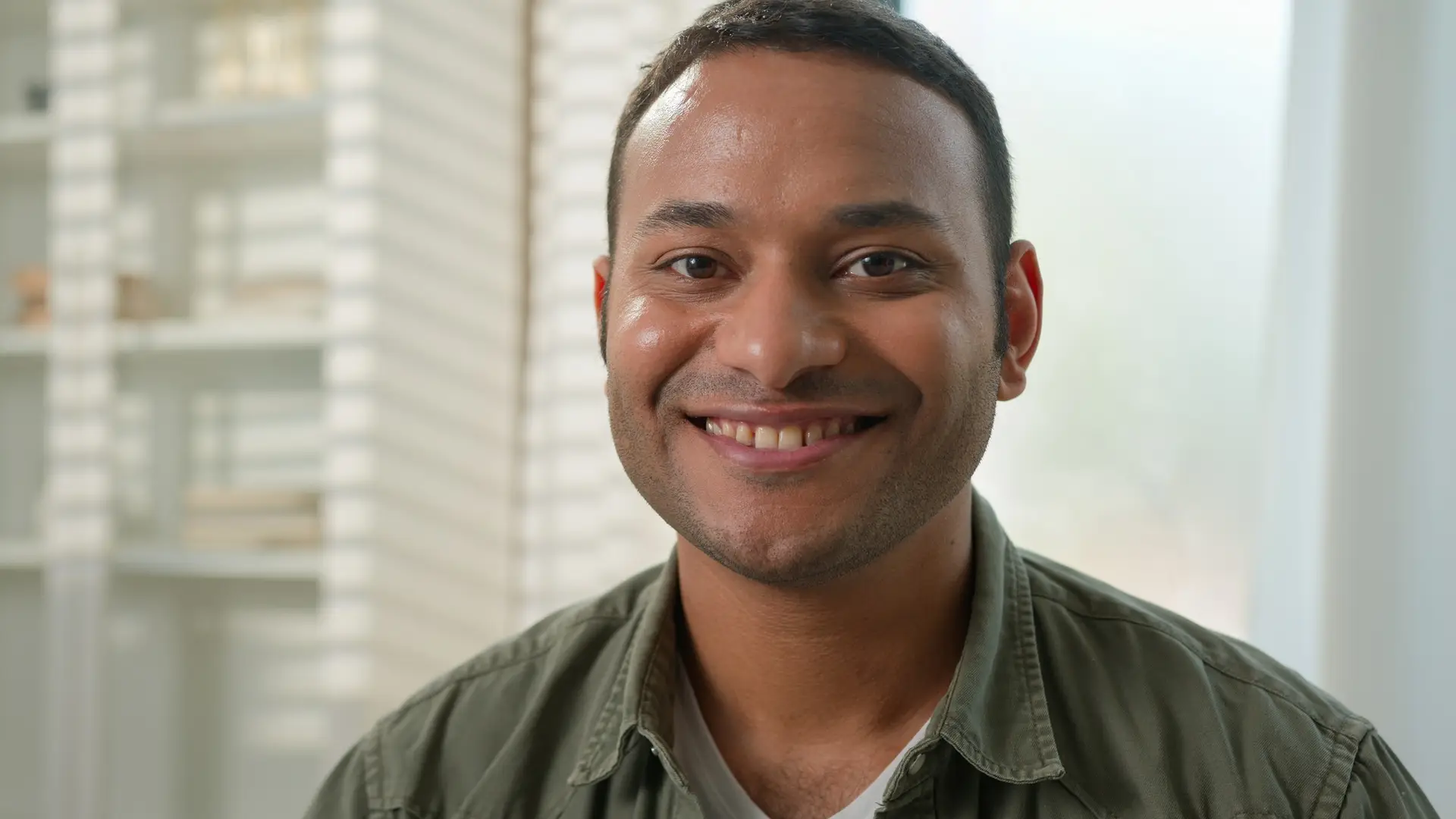 Portrait smiling Indian latin American man happy millennial single guy homeowner in living room